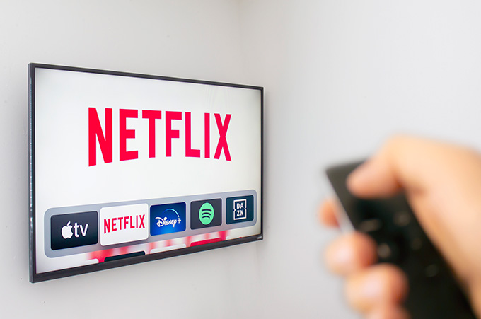 Mano Sosteniendo Control Frente a Pantalla de TV con Netflix