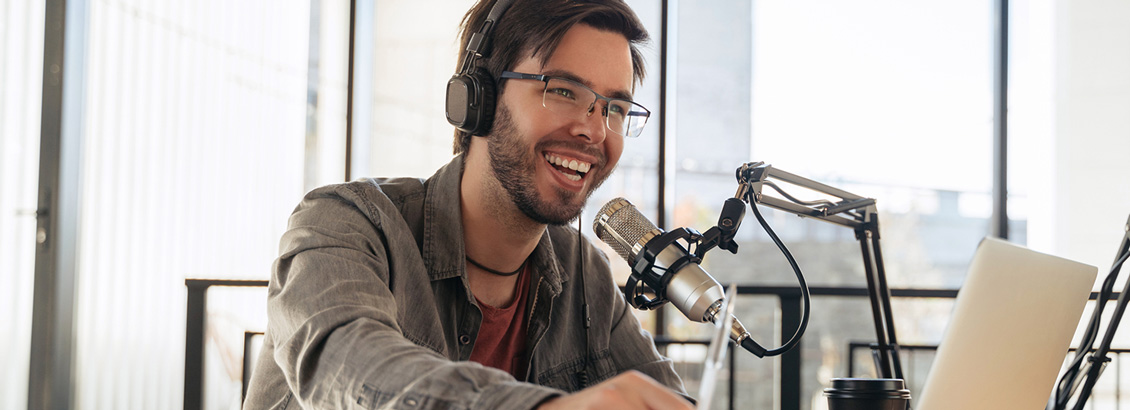 Hombre Sonriente con Audífonos y Micrófoco Para Grabar Podcast