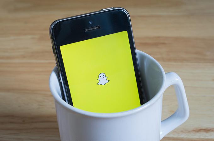 Smartphone, Dentro de Taza de Café Blanca, que Muestra Snapchat en su Pantalla