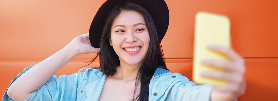 Mujer Joven Sonriente y con Sombrero Tomándose un Selfie