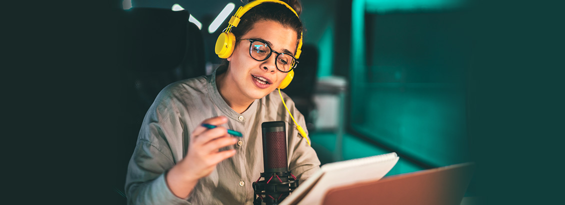 Chica Sentada Frente a Escritorio con Micrófono Mientras Graba Podcast