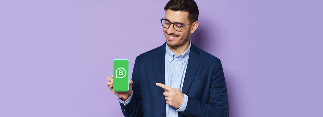 Empresario Apuntando a Smartphone con Logo de WhatsApp Business en Pantalla