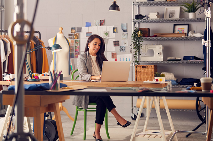 Emprendedora en su Taller de Modas Sentada Frente a Laptop