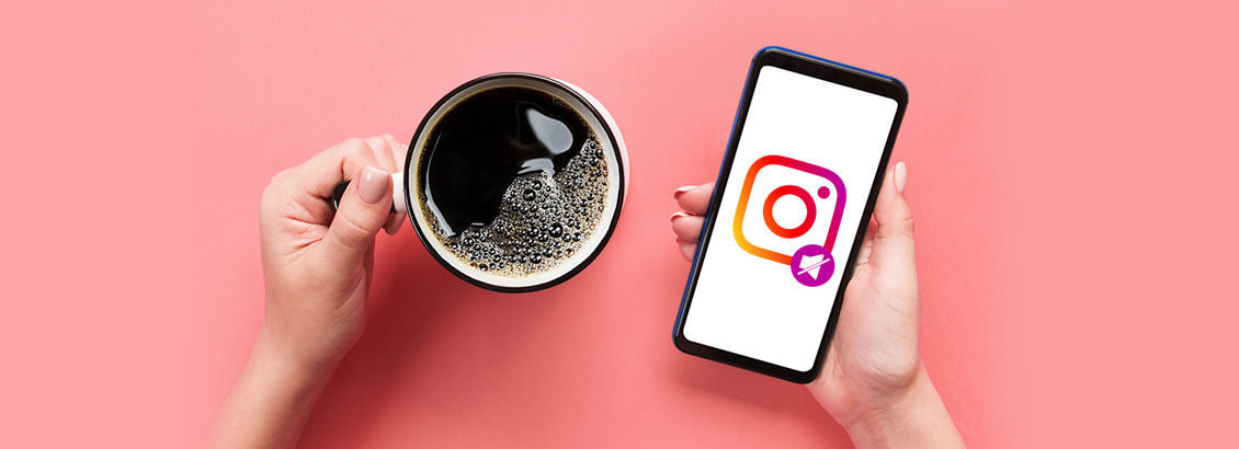 Chica Sosteniendo Taza de Café con una Mano y con Otra Smartphone Mostrando Logo de Instagram