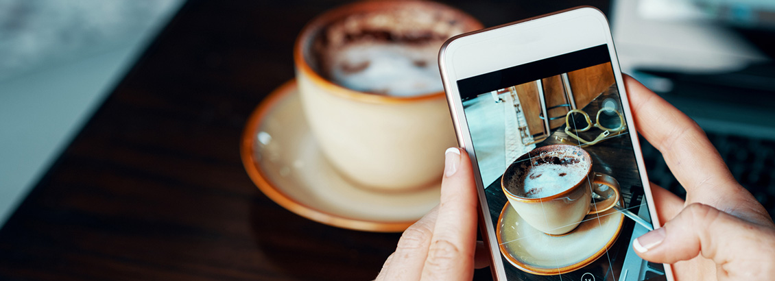 Toma Cercana de Manos Sosteniendo Smartphone que Fotografía un Café