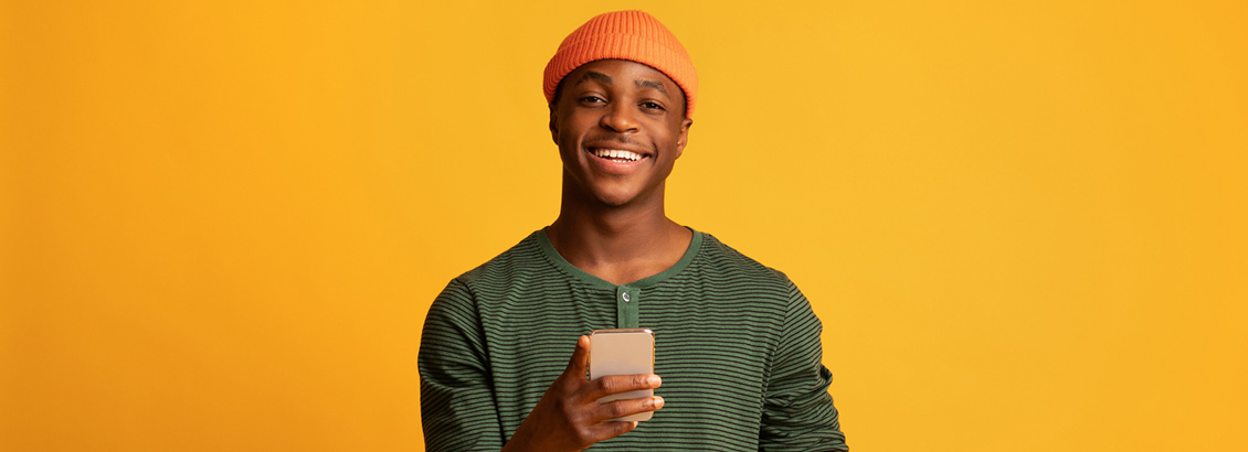 Plano Medio de Hombre Joven Sonriendo con Smartphone en su Mano